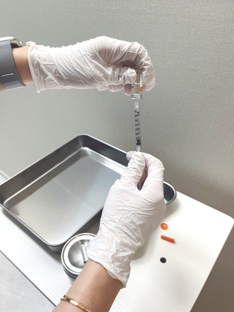 A gloved hand drawing pharmacopuncture solution from a vial into a fine syringe