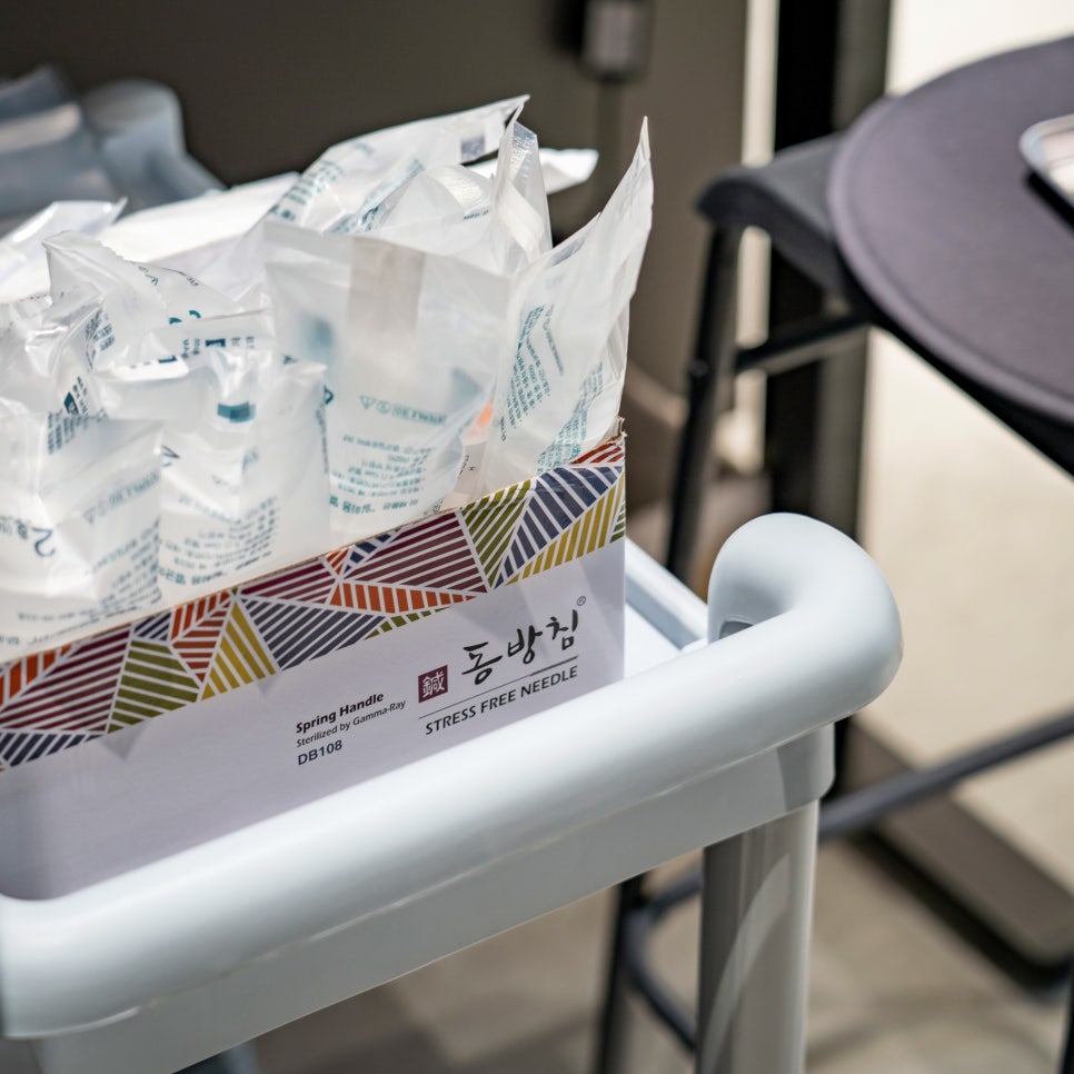 Sterile single-use acupuncture needles in their packaging on a treatment cart